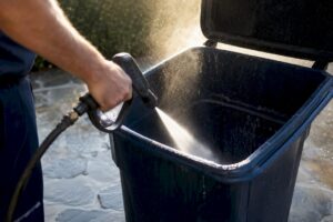 Pressure washing inside residential trash bin