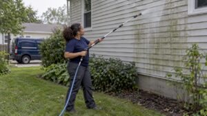 Technician soft washing shaded home siding